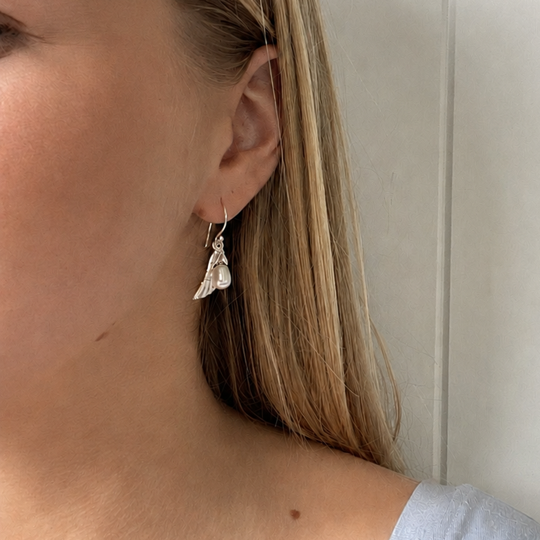 Close-up of a model wearing Angel Wing Earrings Silver with a delicate pearl drop.
