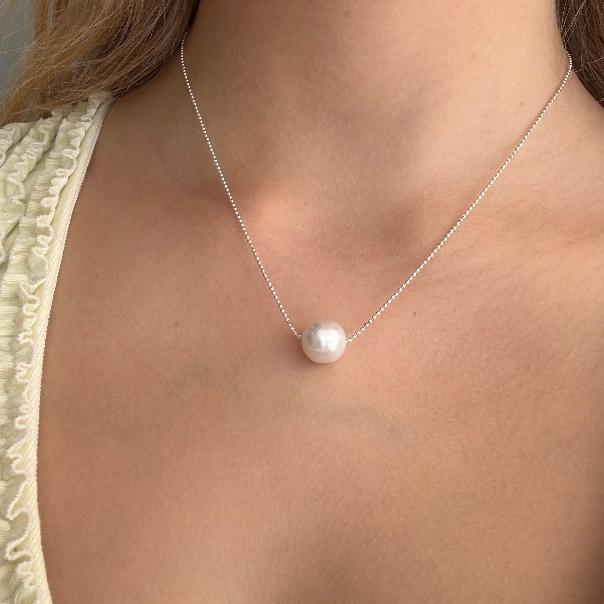 White pearl necklace with delicate sterling silver chain and single round south sea pearl, modelled on a woman. Lush Designs Jewellery Australia.