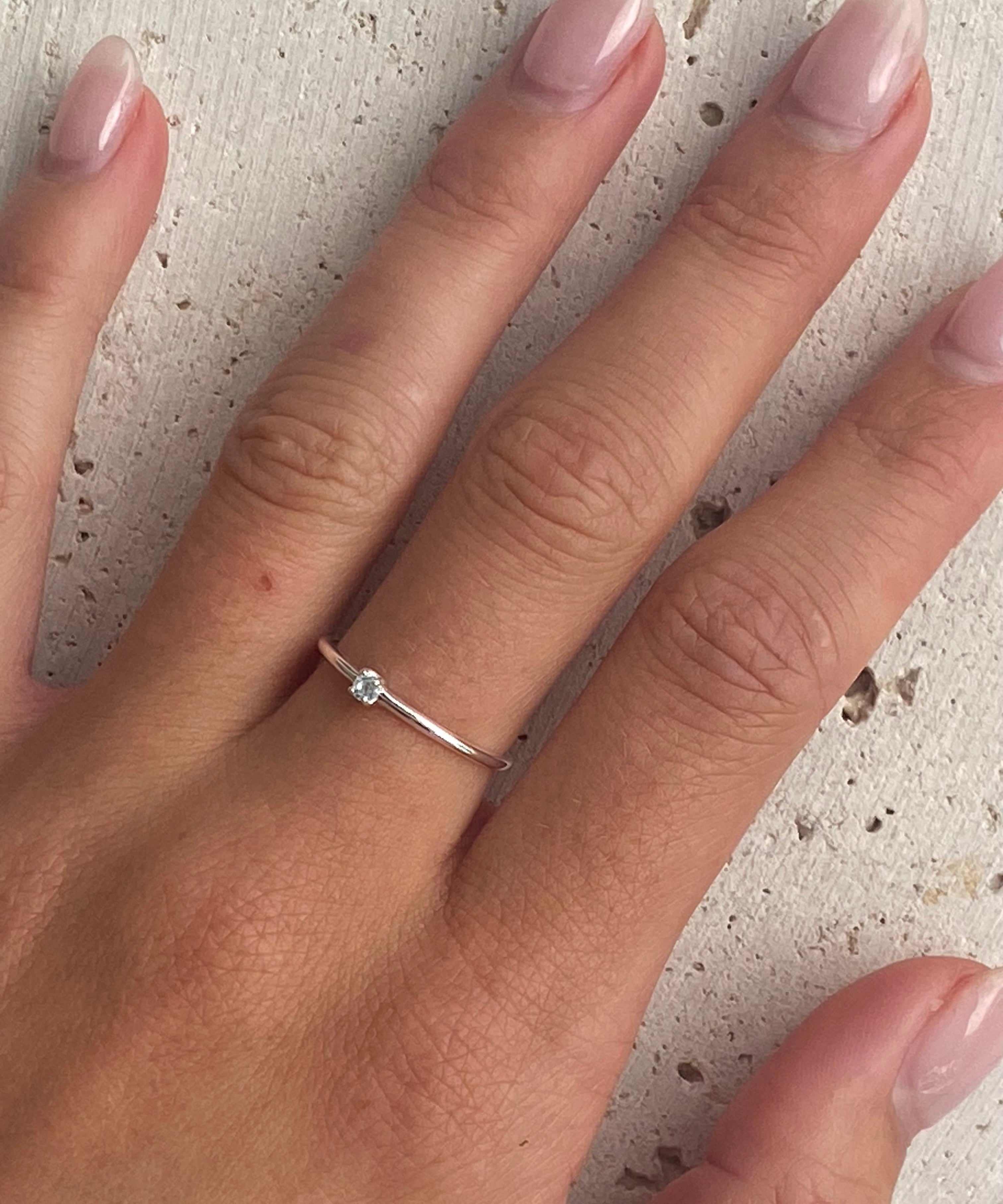 A silver dainty ring with a topaz light blue stone.