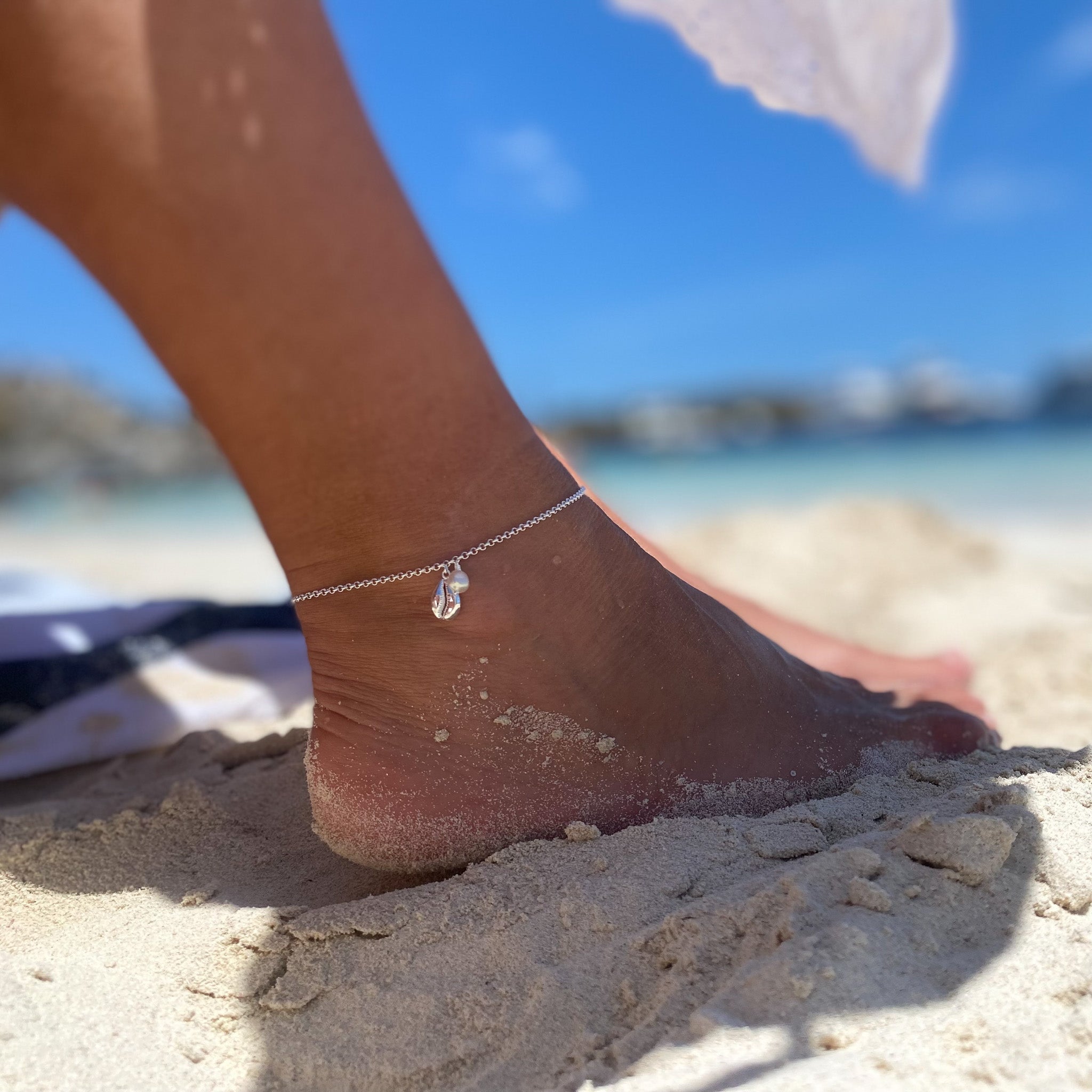Beach Dreams Cowrie Shell Pearl Anklet Silver styled barefoot at the beach, featuring sterling silver, cowrie shell pendant and delicate white pearls.