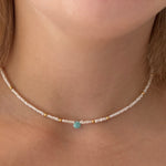 Necklace with a turquoise bead worn by a person