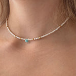 Necklace with a blue gemstone worn by a person