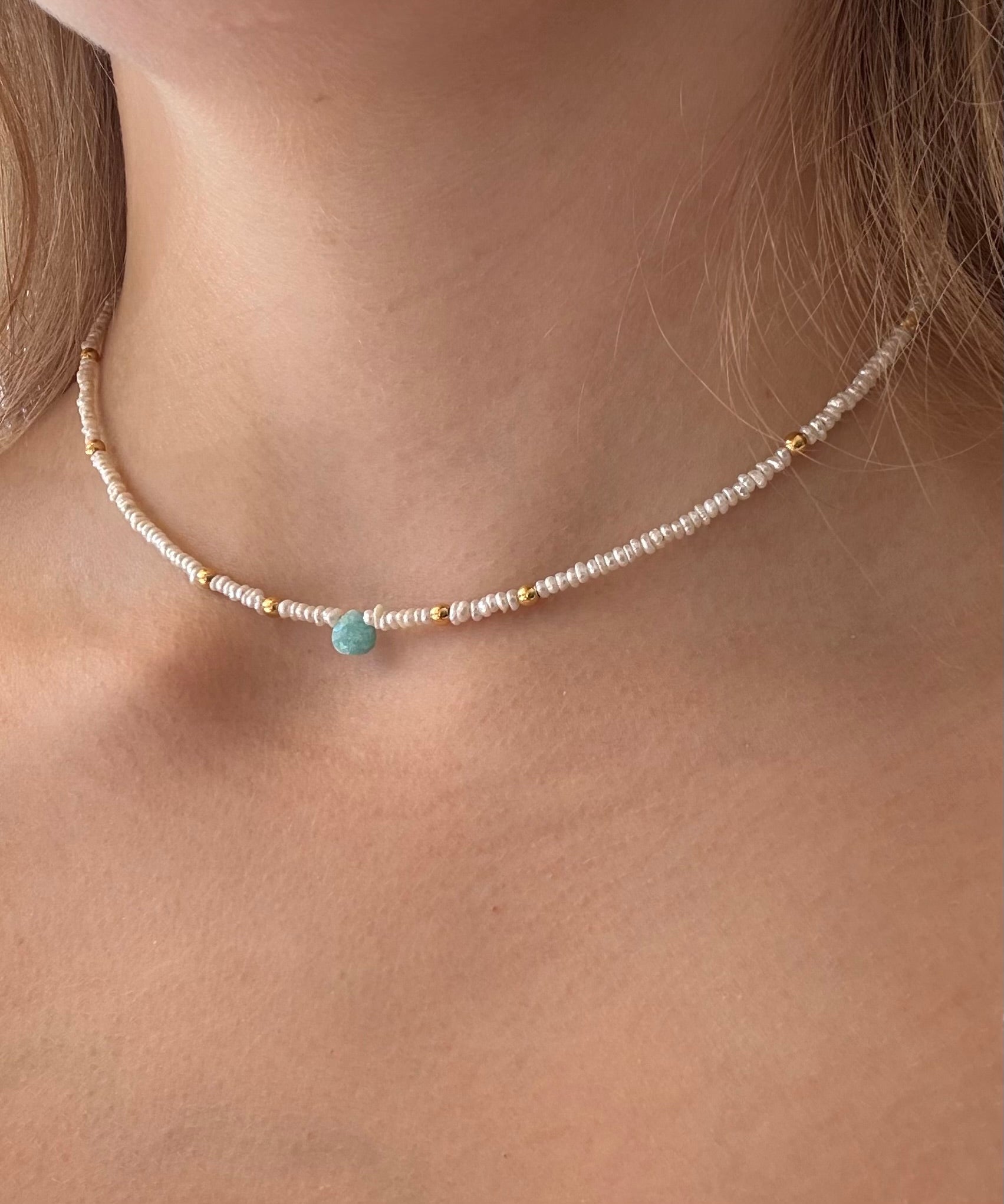 Necklace with a blue gemstone worn by a person