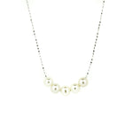 A sterling silver necklace with a chain link design and five rounded freshwater pearls placed along the length of the chain.