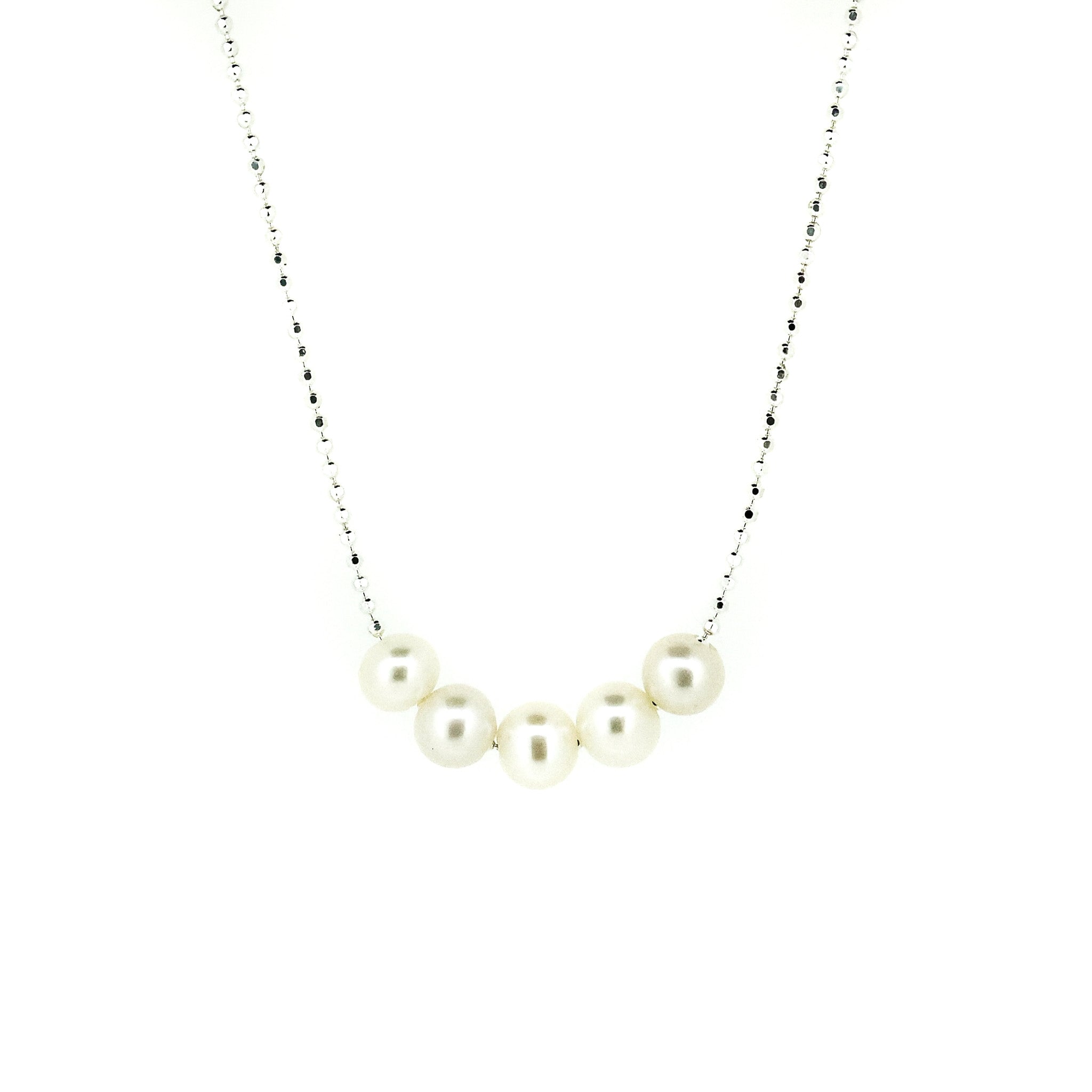A sterling silver necklace with a chain link design and five rounded freshwater pearls placed along the length of the chain.