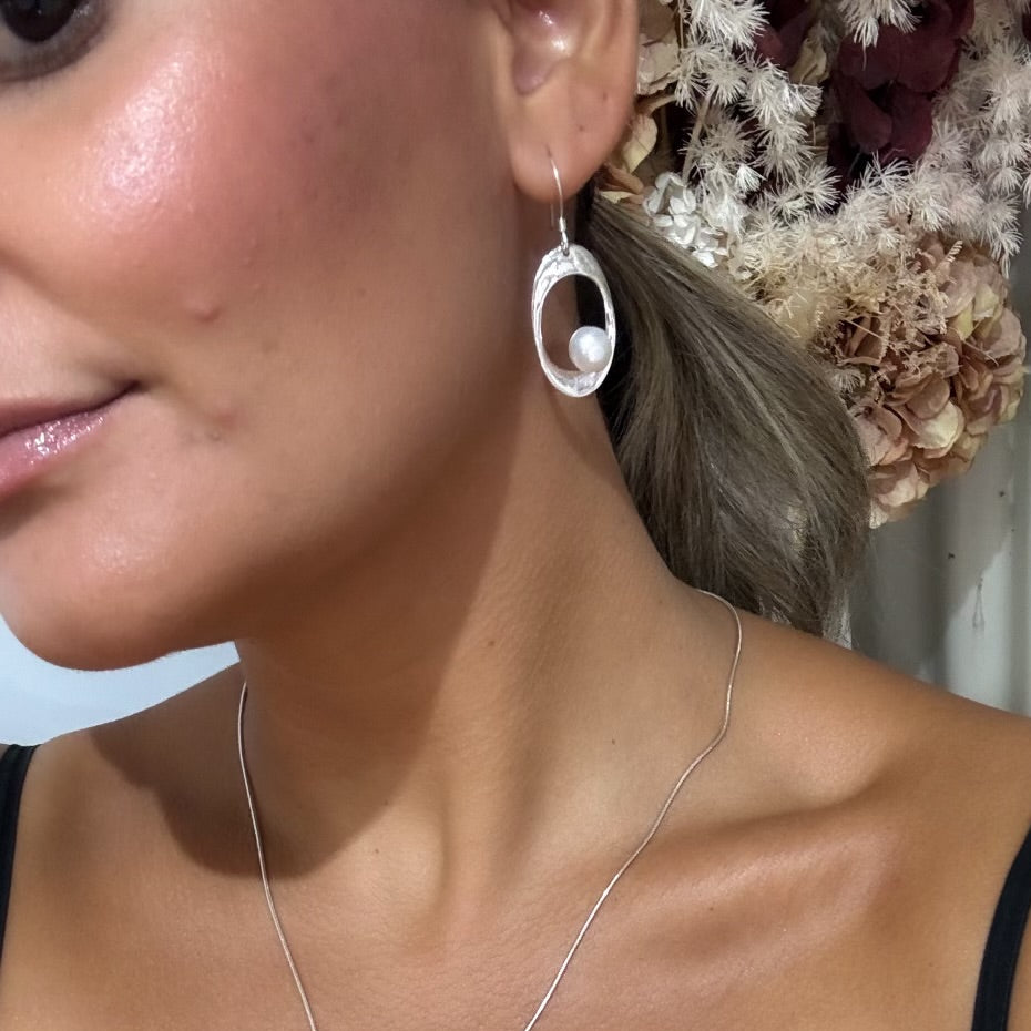 Oval shaped silver earrings with pearl