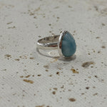 Silver ring with a Larimar stone on a textured beige surface