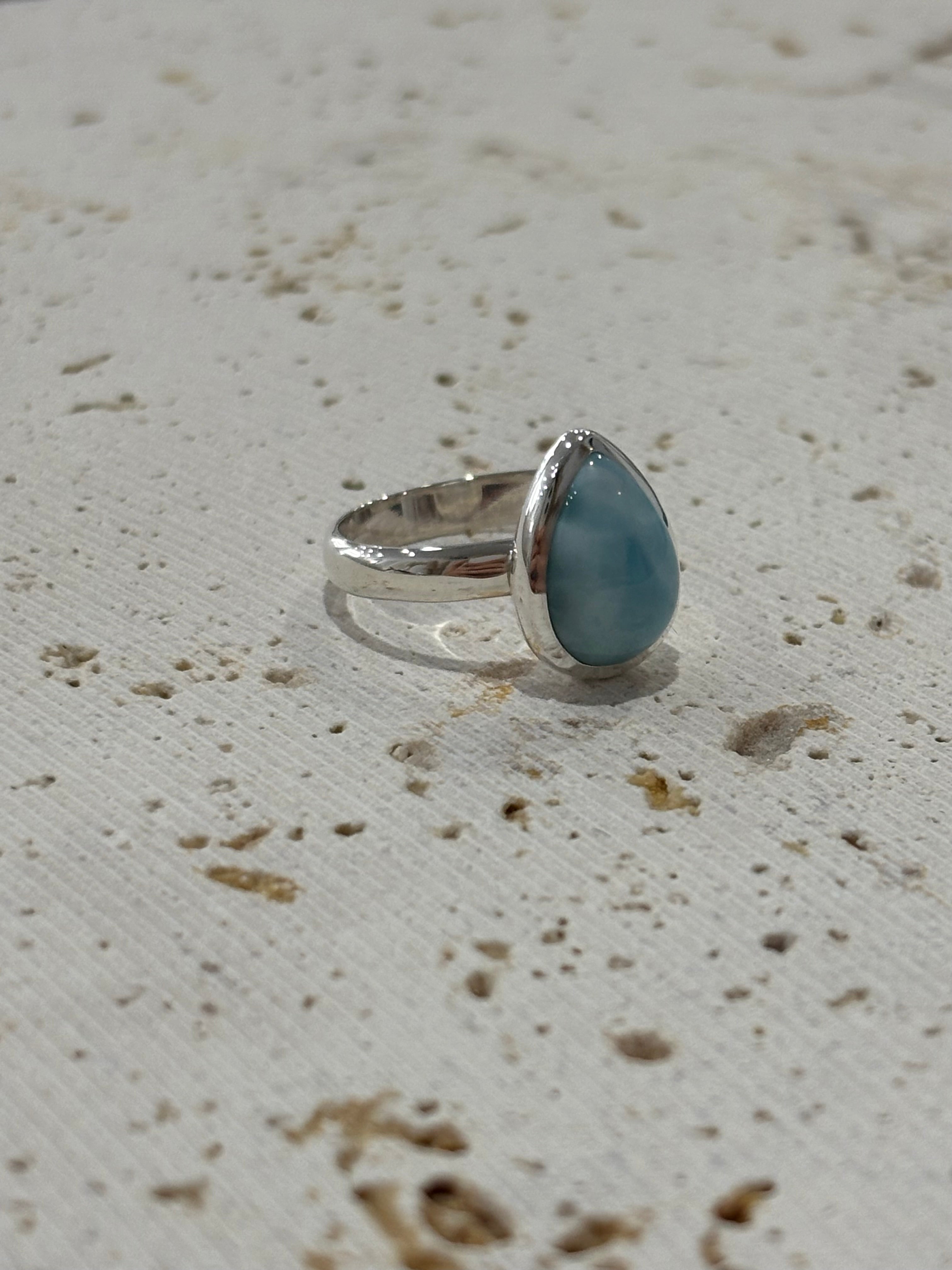 Silver ring with a Larimar stone on a textured beige surface