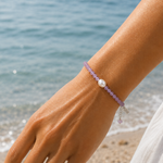 Alt Text:
Pink pearl gemstone bracelet with faceted blush beads, genuine freshwater pearl, sterling silver adjustable chain, and LUSH tag worn on a sun-kissed wrist by the ocean.