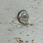 Silver ring with a pearl on a textured beige surface