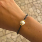 Black neoprene cord pearl bracelet worn on wrist – unisex coastal style