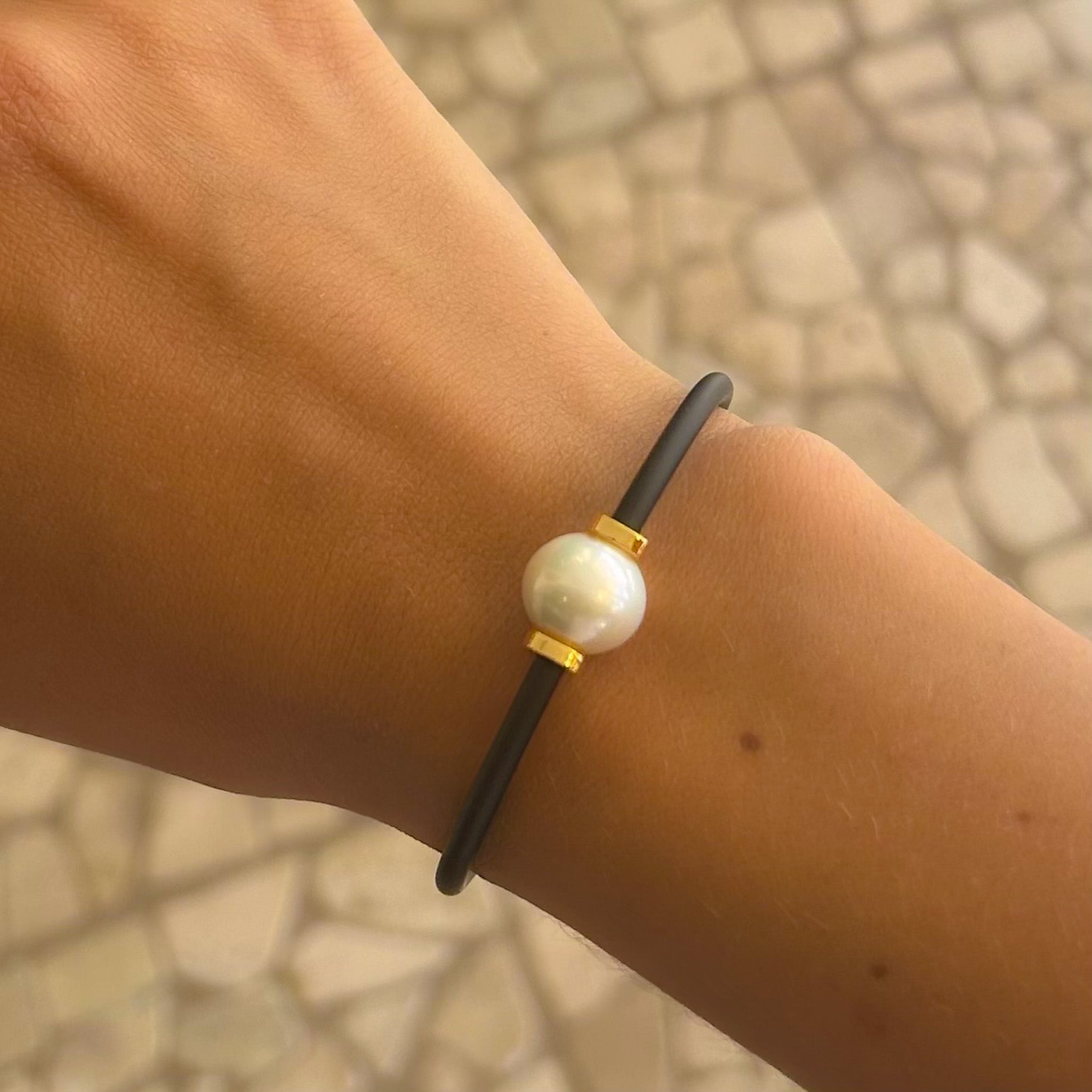 Black neoprene cord pearl bracelet worn on wrist – unisex coastal style