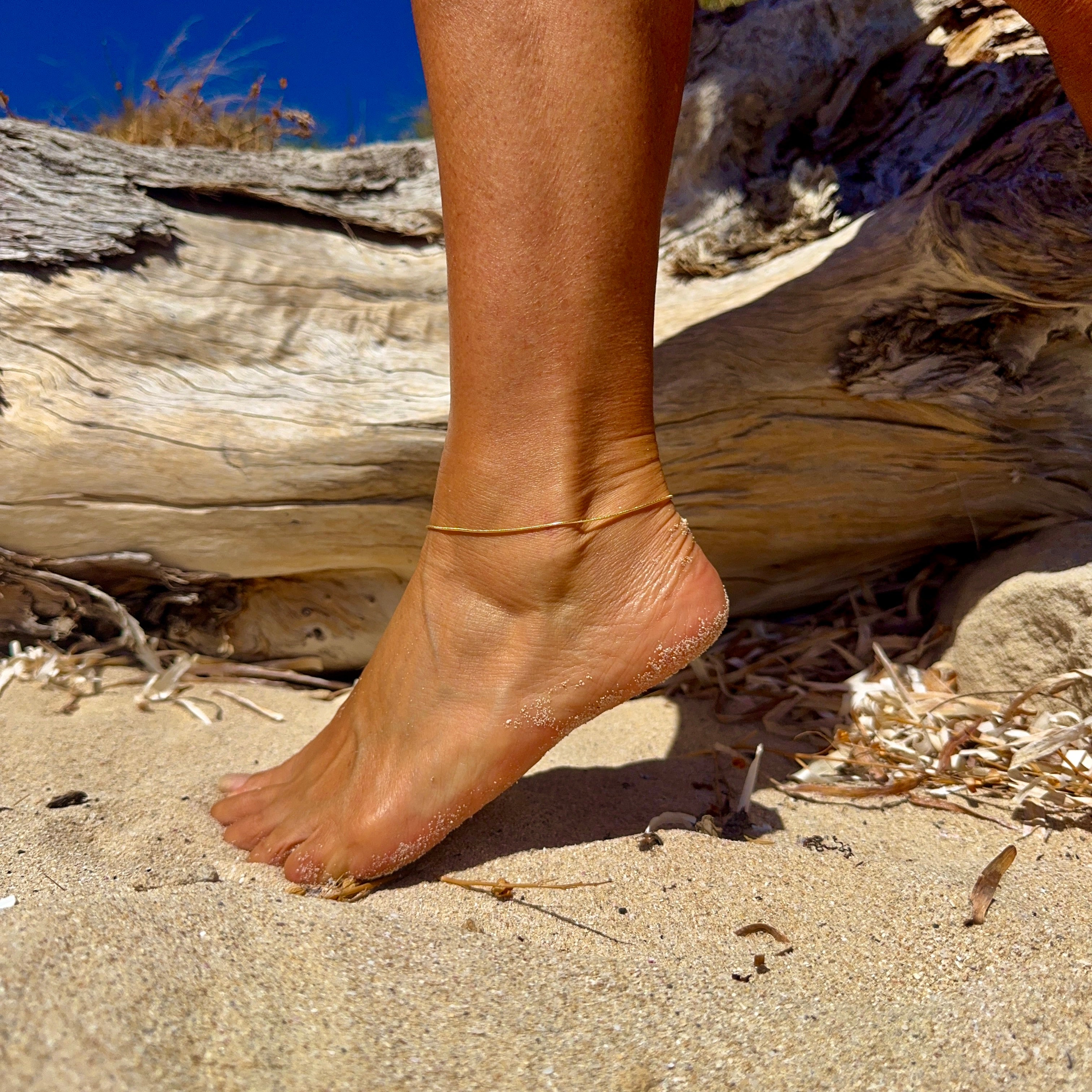 Ocean Current Gold Snake Chain Anklet worn on ankle, featuring a delicate 18k gold vermeil chain for a minimalist coastal jewellery look.
