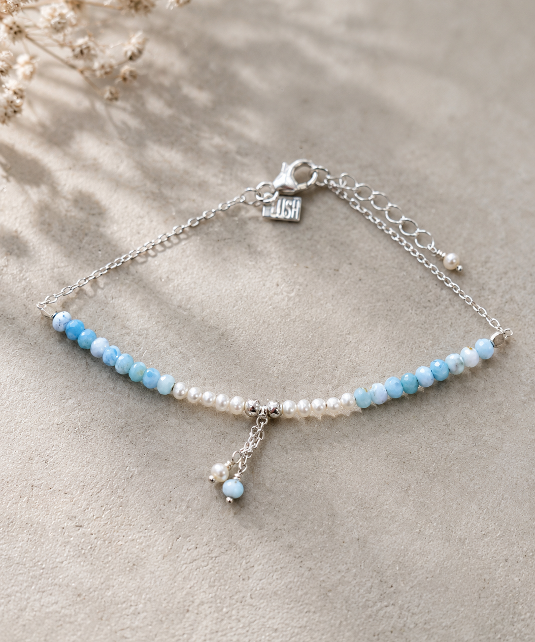 Light blue gemstone and freshwater pearl bracelet featuring delicate white pearls, soft blue beads and sterling silver accents on an adjustable design. A beach-inspired bracelet handcrafted for effortless coastal style.