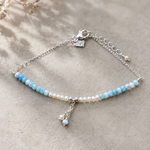 Light blue gemstone and freshwater pearl bracelet featuring delicate white pearls, soft blue beads and sterling silver accents on an adjustable design. A beach-inspired bracelet handcrafted for effortless coastal style.