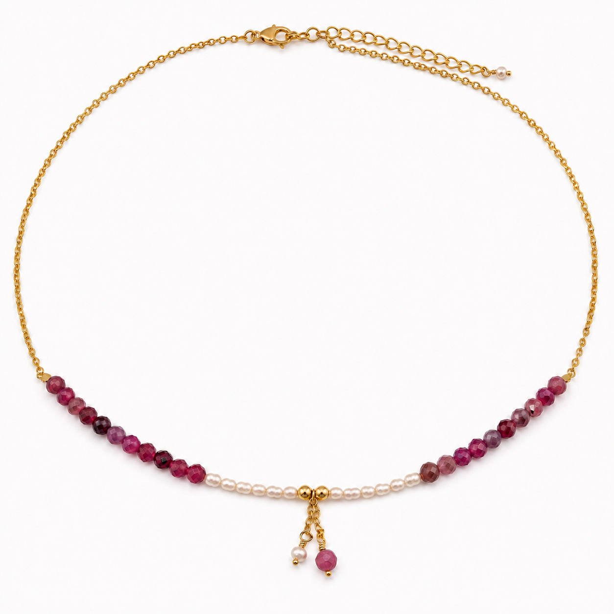 A delicate gold chain necklace featuring a row of ruby beads, pearl beads, and a small dangling charm
