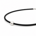 A minimalist black neoprene necklace featuring a single white pearl bead and a silver lobster clasp.