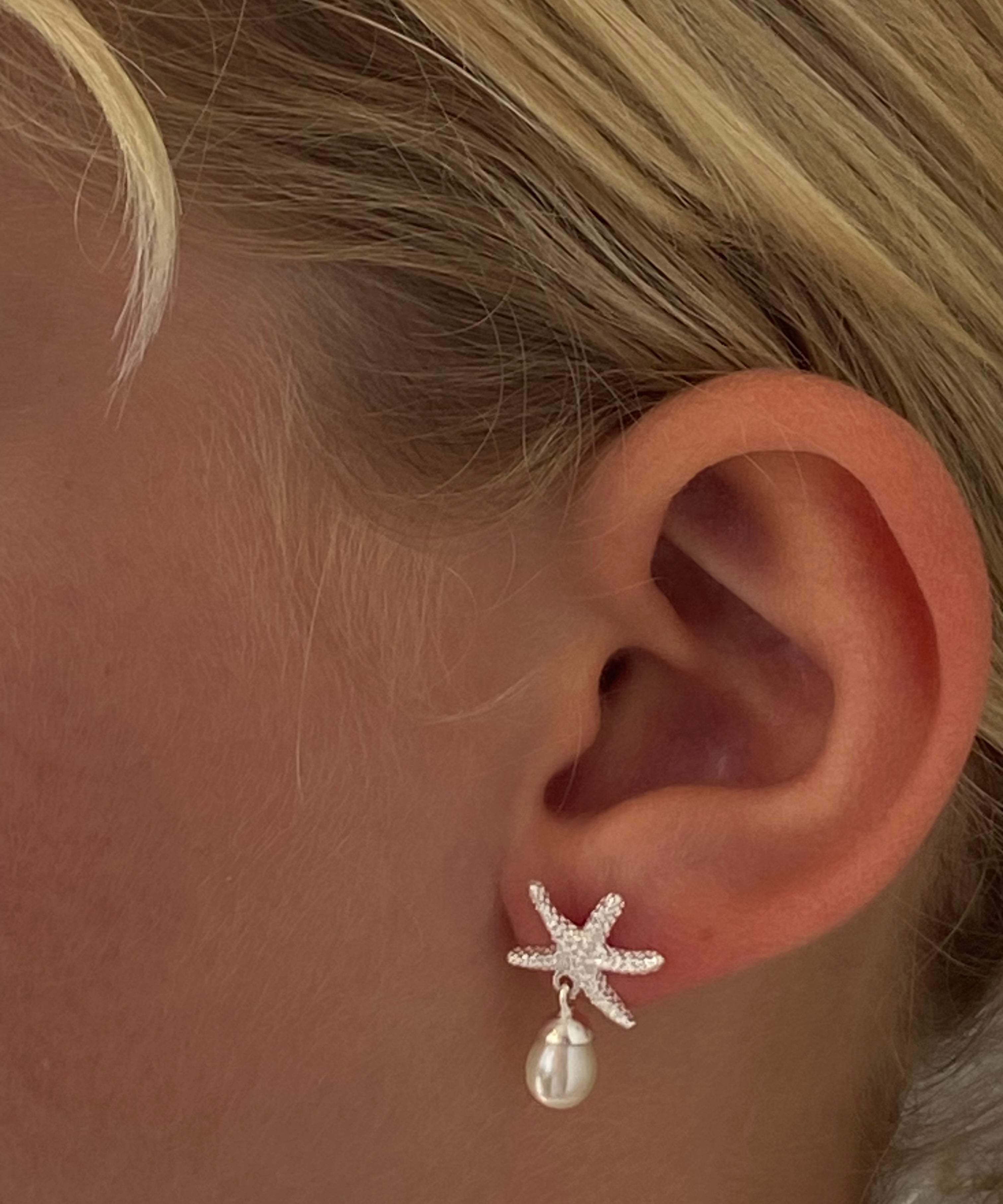 Silver starfish stud earrings featuring a freshwater pearl attached 