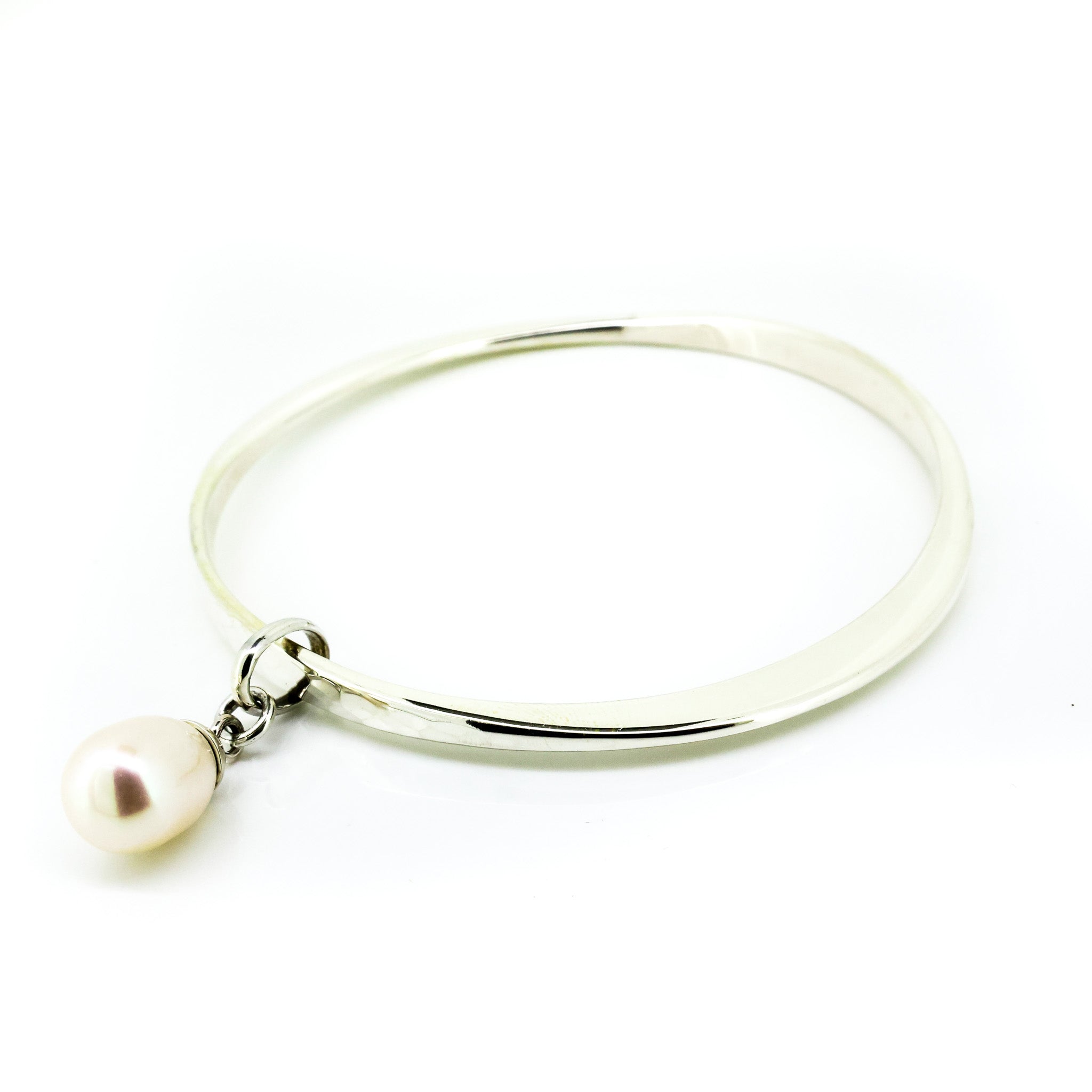 A silver bangle bracelet with an asymmetrical design featuring a luminous pearl charm.