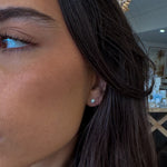Close-up of a person's ear with an earring, blurred indoor background