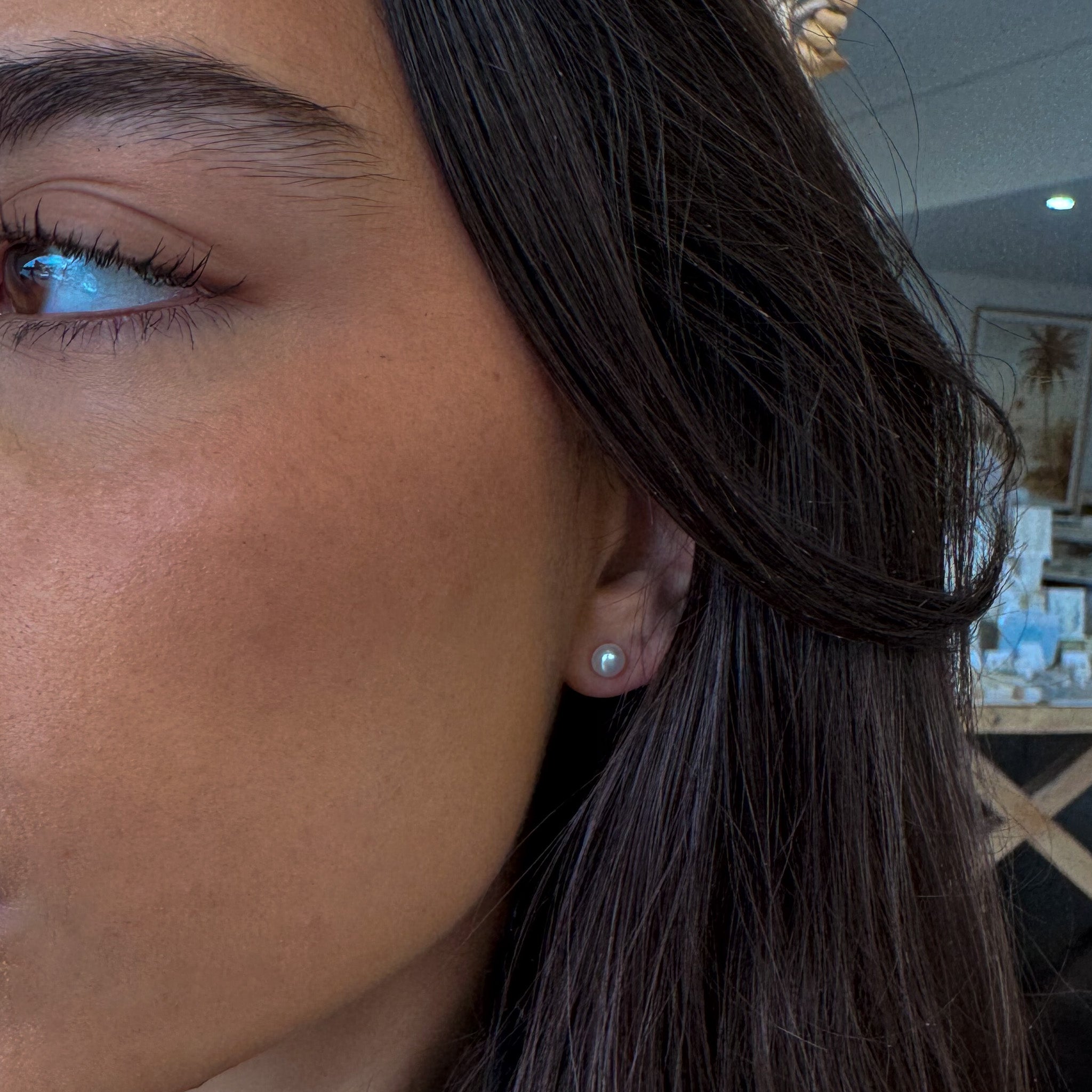 Close-up of a person's ear with an earring, blurred indoor background
