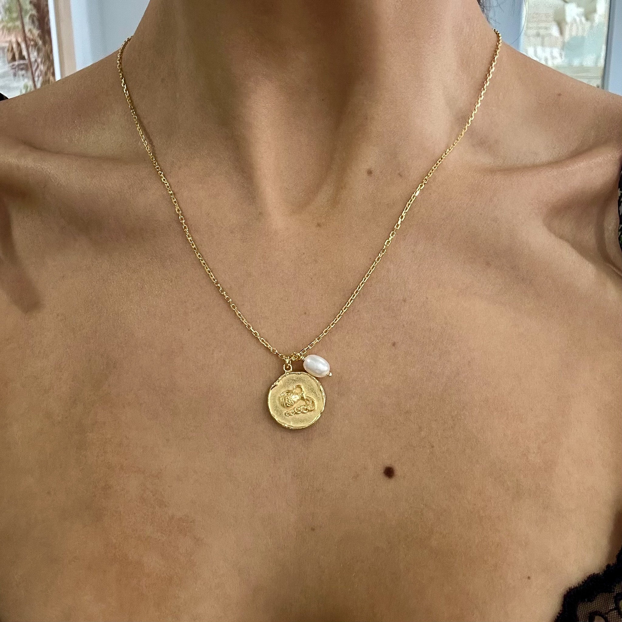 Gold Aquarius zodiac pendant on gold chain necklace 