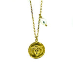 A gold necklace with a round pendant featuring the Aries ram symbol and a lustrous pearl drop at the end.