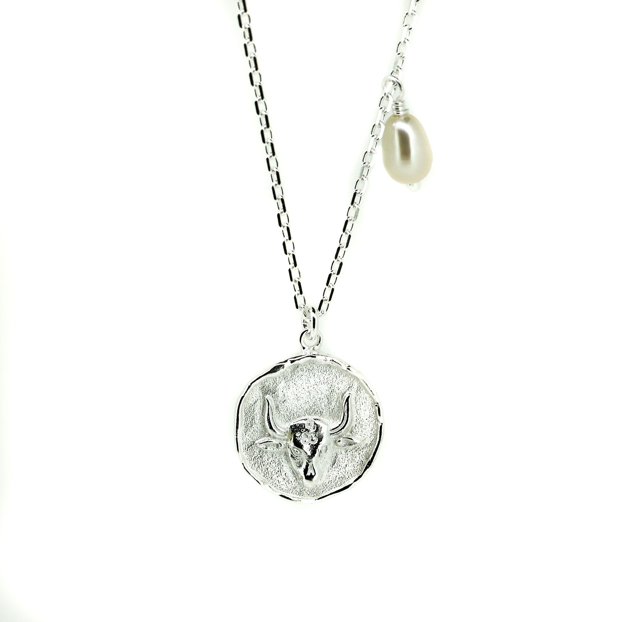 A silver necklace featuring a Taurus bull pendant with a lustrous pearl attached to the top.