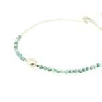 A necklace with blue larimar gemstones and a white keshi pearl, with small blue and white pearls strung along a fine chain.