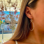 A person wearing hoop earrings made of sterling silver.