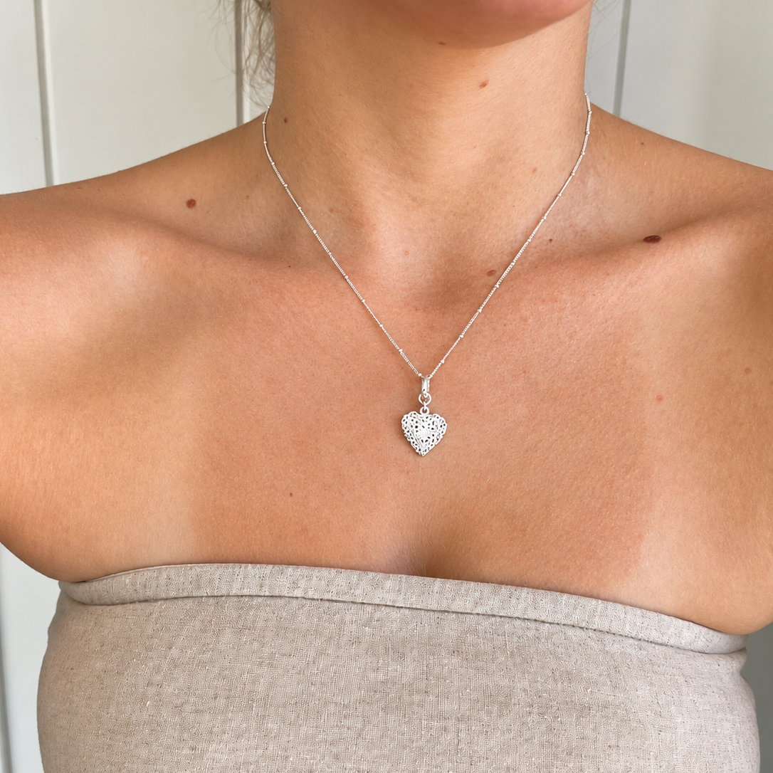 Model wearing a delicate sterling silver filigree heart pendant on a fine silver chain, featuring intricate floral cut-out detailing. Coastal-inspired jewellery by Lush Designs Jewellery Australia.