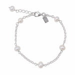 A silver chain bracelet with six white freshwater pearls spaced evenly along the chain, featuring a lobster clasp, extender chain, and a small engraved brand tag that reads 'LUSH'.
