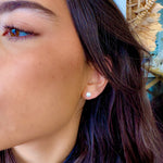 Close-up of a person wearing a pearl earring with a blurred background