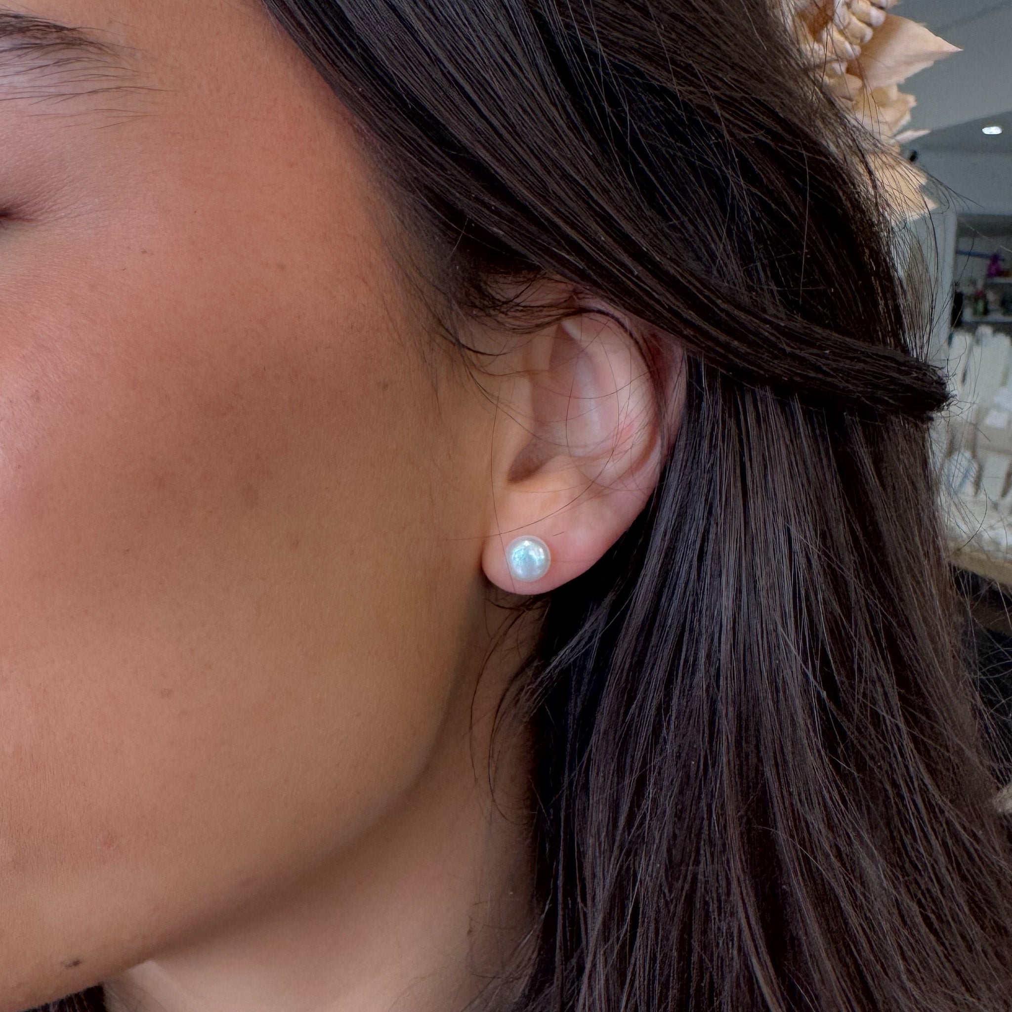 Close-up of a person wearing a light blue earring with a blurred background