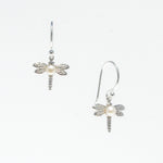 A pair of sterling silver hook earrings featuring a detailed dragonfly design with a freshwater pearl positioned at the center of the dragonfly's body.