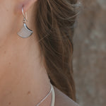 A pair of sterling silver earrings featuring large white mother of pearl shells shaped in a fan 