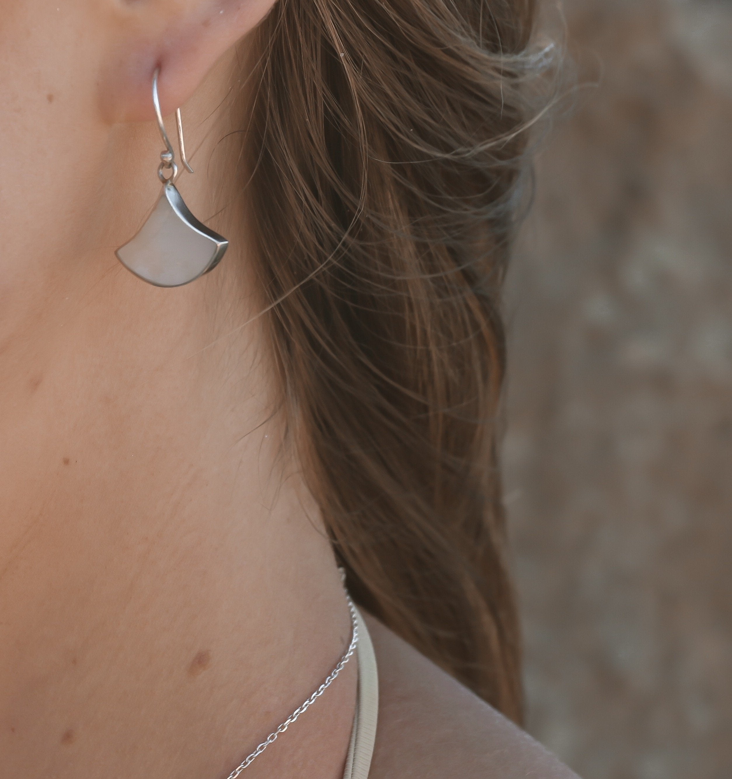 A pair of sterling silver earrings featuring large white mother of pearl shells shaped in a fan 