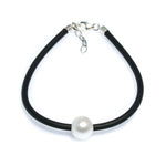 Minimal pearl bracelet on black neoprene cord worn on wrist – coastal style