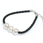 Triple pearl bracelet on black braided cord worn on wrist – coastal style