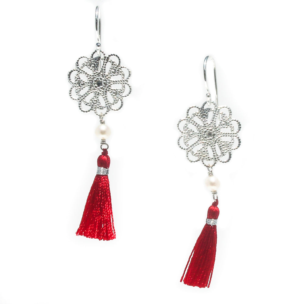 A pair of silver disc earrings with pearl details and red tassel accents
