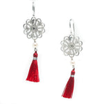 A pair of silver disc earrings with pearl details and red tassel accents