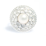 A sterling silver ring with a detailed circular design and a central white freshwater pearl, isolated on a white background.